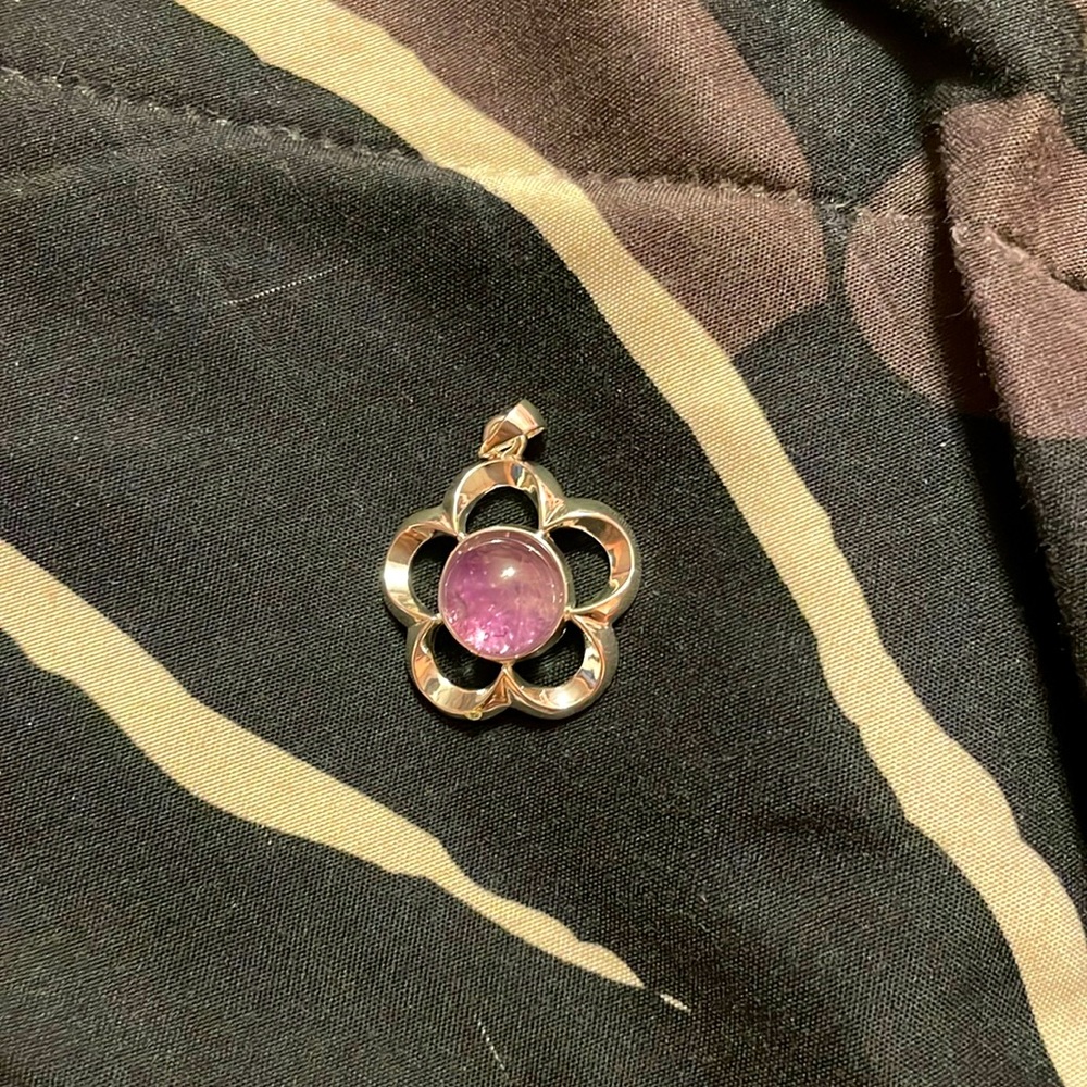 Beautiful silver flower pendant with purple crystal in the center.